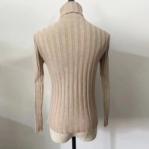 Detail showing the ribbed vertical texture and high neck of the beige knitted sweater