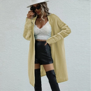 Detail of a beige cable-knit cardigan showing loose-fit texture and drop shoulder design