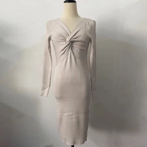 Détail du col en V torsadé et de la maille côtelée sur cette robe mi-longue crème