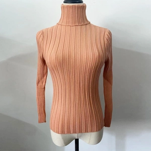 Close-up of peach-pink turtleneck knit sweater featuring ribbed texture and slim-fit cut