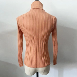 Detail of salmon pink ribbed knit sweater with a high turtleneck collar and textured fabric