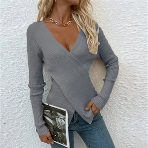 Détail de la maille côtelée et du design croisé sur un pull gris ajusté à manches longues