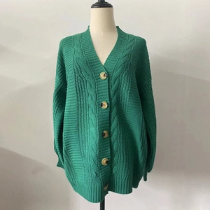 Detail shot of green cable knit cardigan showing thick texture and brown buttons