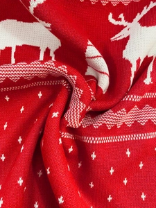 Close-up of red and white knitted Christmas sweater with reindeer and snowflake patterns