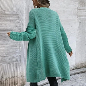 Detailed close-up of light green oversized knit cardigan with textured wave sleeve pattern