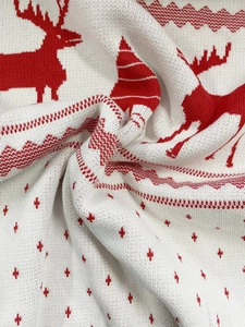 Detailed close-up of knit fabric showing red reindeer and Christmas tree jacquard patterns