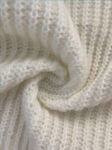 Close-up of the chunky cream-white knit fabric texture on this stylish turtleneck sweater