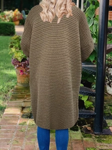 Detail der olivgrünen Stricktextur an einer langen, übergroßen Strickjacke
