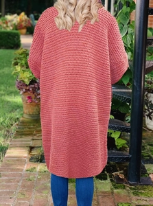 Detailaufnahme der langen Strickjacke mit grober Wellenstruktur in Korallenrosa