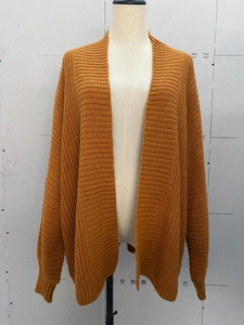 Detailed close-up of ginger knit cardigan showing ribbed cuffs and textured stitch pattern