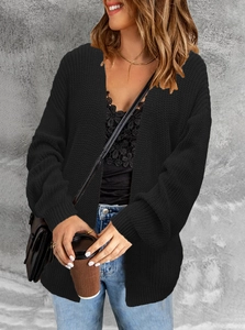 Detail of chunky black knit cardigan showing texture, ribbed cuffs and cable patterns