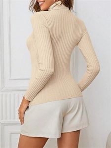 Close-up of ribbed knit texture on a beige turtleneck sweater showing back and side profile