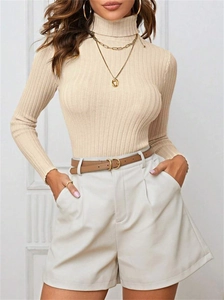 Detail of beige ribbed turtleneck knit sweater paired with high-waisted shorts and belt