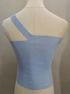Dettaglio del top in maglia a coste azzurro con taglio asimmetrico sulla spalla