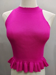 Detail of rose red sleeveless knit top featuring a ribbed texture and ruffled hemline