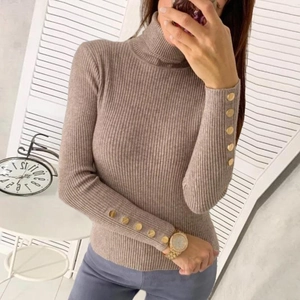 Detail of taupe ribbed turtleneck sweater featuring elegant gold buttons on sleeve cuffs