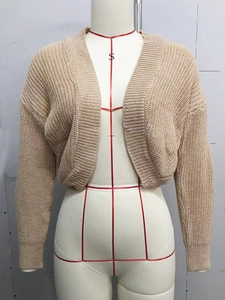 Close-up of beige chunky knit texture and ribbed cuffs on a short women's cardigan