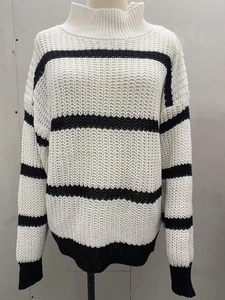 Détail d'un pull en grosse maille à rayures noires et blanches avec col montant et bord-côtes