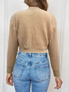 Detail of beige knit cardigan sweater featuring ribbed cuffs and soft textured fabric