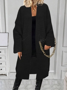 Dettaglio del cardigan oversize nero a maglia grossa con ampie tasche anteriori