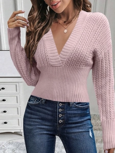 Detail of pink V-neck knit sweater with crossover design and ribbed cuffs on female model