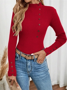 Detail of red ribbed knit sweater featuring elegant metal buttons on high neck and cuffs