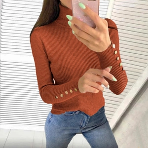 Close-up of caramel knit sweater with vertical texture and gold buttons on cuffs