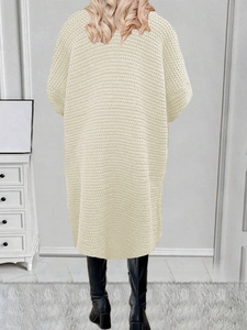 Dettaglio posteriore di un cardigan lungo in maglia grossa color panna con trama strutturata