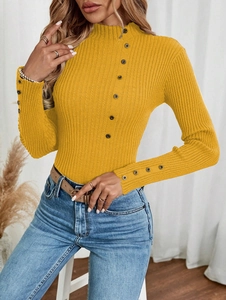 Close-up of yellow ribbed knit sweater with decorative buttons on collar and cuffs