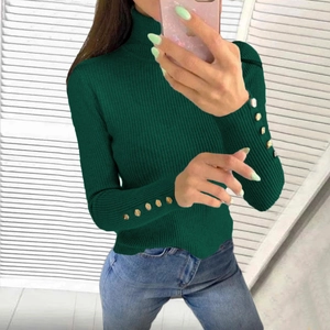 Detail of dark green ribbed knit sweater with decorative gold buttons on sleeves