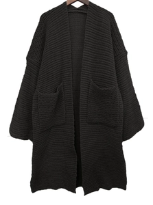 Dettaglio di un lungo cardigan nero a maglia con texture e grandi tasche laterali