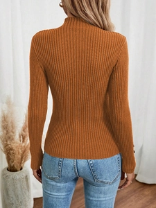 Detail of caramel rib-knit sweater featuring elegant decorative buttons on sleeve cuffs
