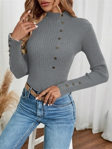 Close-up of gray ribbed knit sweater with decorative buttons on collar and cuffs