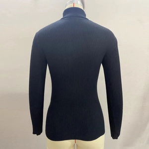 Detail of black turtleneck sweater featuring ribbed knit texture and fitted back design