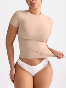 Vista detallada de la camiseta beige ajustada con tejido de alta elasticidad en una modelo