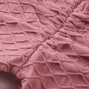 Dettaglio dei pantaloni da yoga rosa con trama a rombi 3D e design a vita alta sportivo