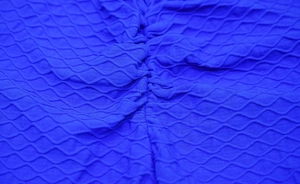 Dettaglio della trama a nido d'ape e arricciatura dei leggings yoga blu modellanti