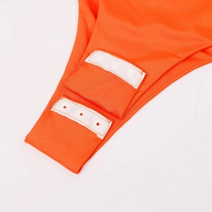 Detail view of the orange bodysuit featuring a three-button snap closure at the crotch