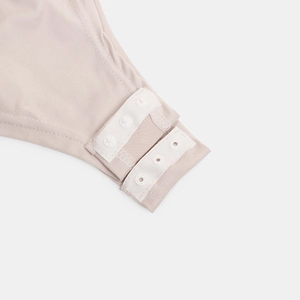 Detailed macro view of the snap button closure on a soft pink stretch fabric bodysuit