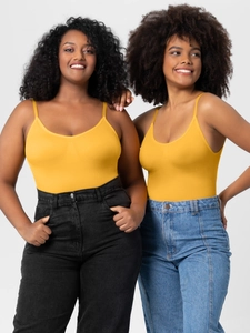 Detail of yellow seamless shapewear bodysuit styled with high-waisted denim jeans