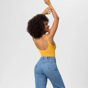 Close-up of a bright yellow backless bodysuit paired with light blue denim jeans