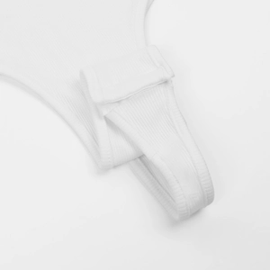 Detailed macro view of white ribbed bodysuit fabric with convenient snap closure at the bottom