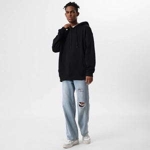 Detailed view of black loose hoodie paired with distressed light blue denim jeans