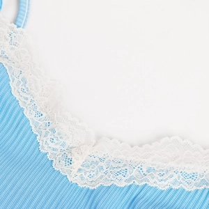 Détail macro du tissu côtelé bleu ciel avec bordure en dentelle blanche sur le haut