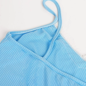 Détail de caraco en maille côtelée bleu clair avec bordure et bretelles en dentelle
