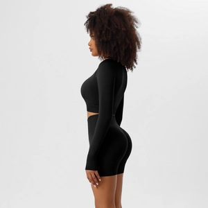 Side view of seamless black yoga set featuring long sleeve crop top and high waist shorts