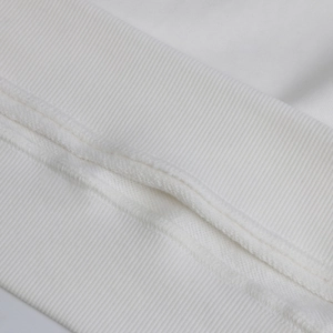 Detailed macro view of the ribbed cuffs and high-quality stitching on white cotton sweater
