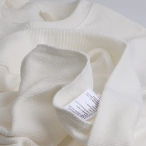 Close-up detail of the ribbed neckline and care label on white heavy cotton sweatshirt