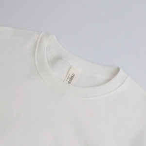 Detail of white cotton crew neck sweatshirt showing ribbed collar and premium neck label