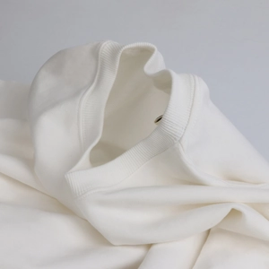 Detailed close-up of a white heavy cotton sweatshirt featuring a ribbed crew neck design